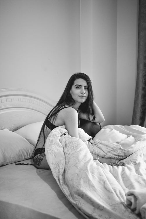 Free Elegant black and white portrait of a woman sitting on a bed showcasing elegance and intimacy. Stock Photo