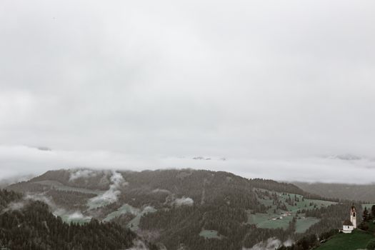 薄雾笼罩的山区，景色宁静，一座古色古香的教堂坐落在绿色的森林中