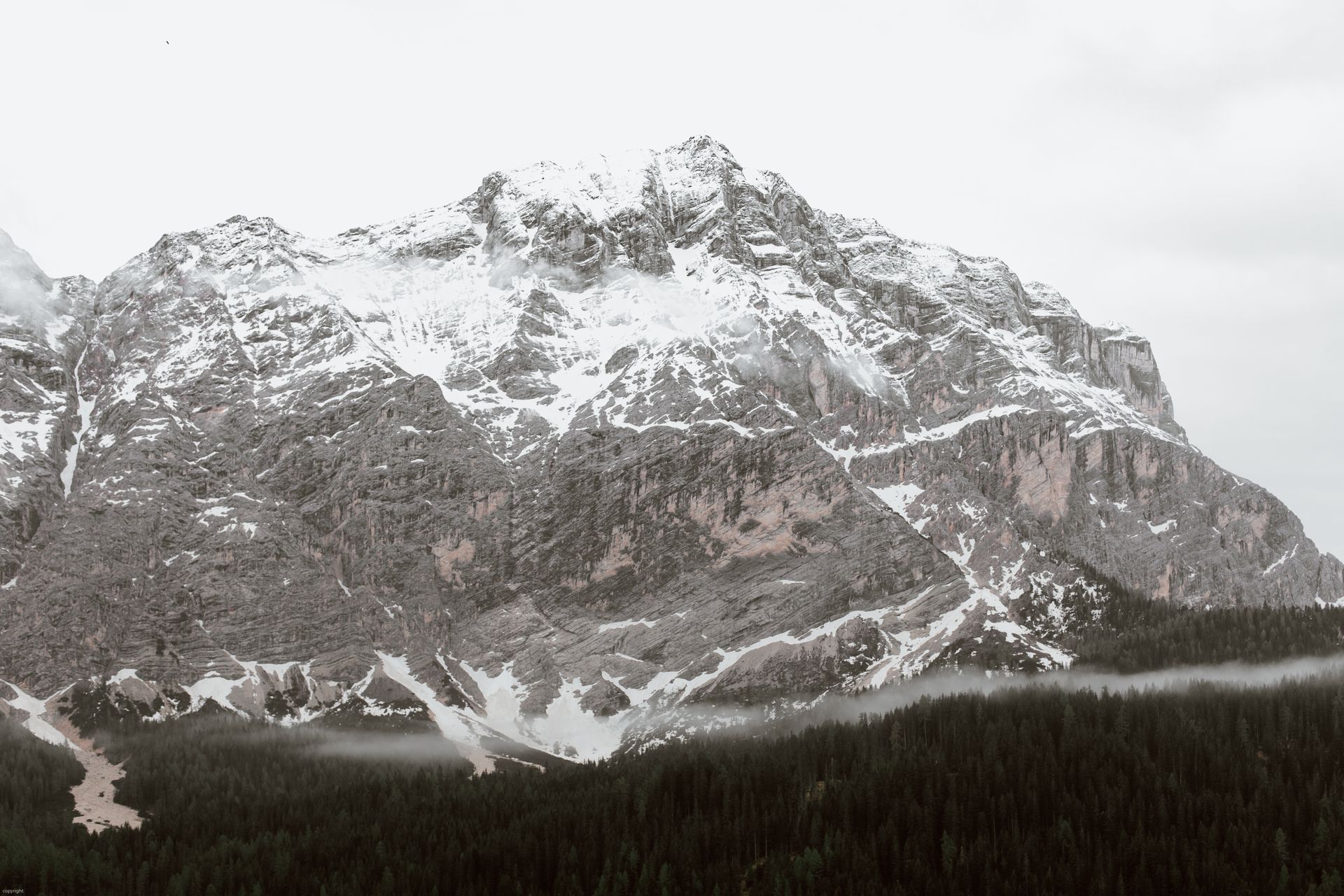 Breathtaking snowy mountain range with forest backdrop, serene and picturesque winter scene.