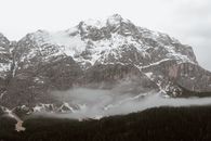 阴沉的冬日，灰色的云漂浮在白雪覆盖的山区山谷中那片郁郁葱葱的针叶林上空