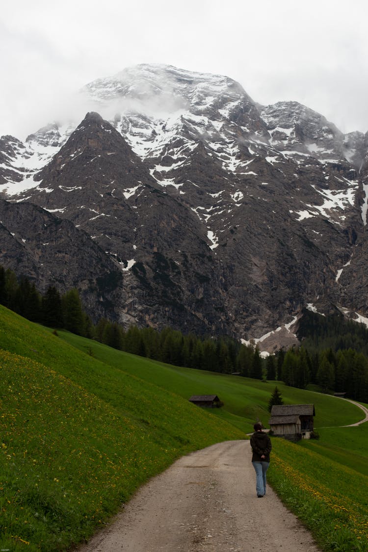 Unrecognizable Person Walking Along Hilly Terrain In Mountainous Valley