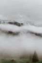 薄雾笼罩着宁静的山区，一座木屋坐落在郁郁葱葱的绿色原野中