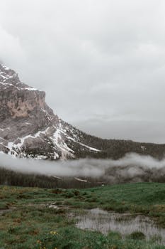 阴天浓雾中，山脊积雪与沼泽地形构成一幅如画风景