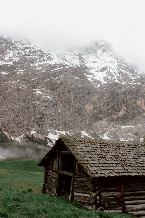 Lonely wooden house in green valley with mountains