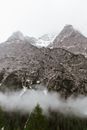 雾天的早晨，常绿森林附近，白雪皑皑的山峰耸立于陡峭的山坡上，景色令人惊叹