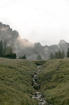 山景宁静，雾气缭绕，小溪潺潺，小屋孤寂