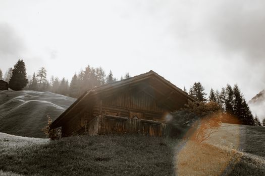 小化风村屋坐落在绿色丘陵山谷中，四周环绕着针叶林，天色阴沉