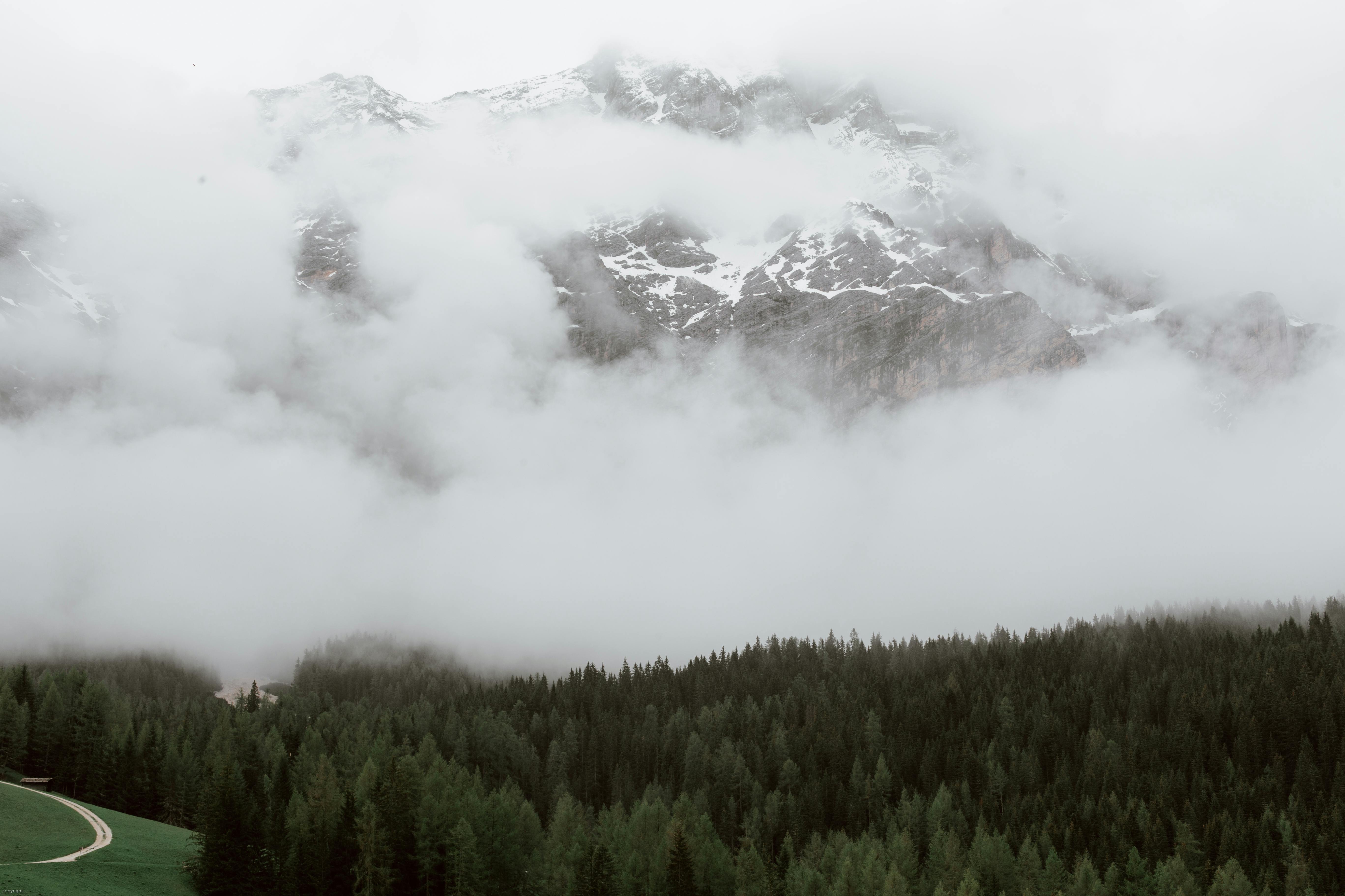 Prescription Goggle Inserts - Breathtaking scenery of dramatic snowy mountain range covered with dense fog located near evergreen lush forest and narrow curvy road