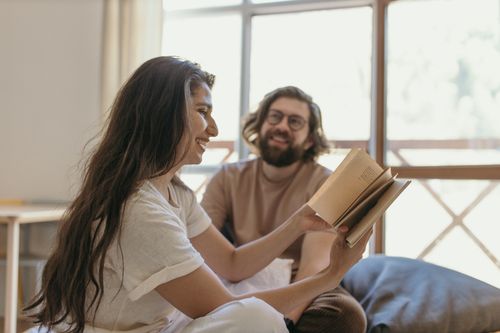 Free Couple seated indoors sharing a joyful moment with vintage books and laughter. Stock Photo