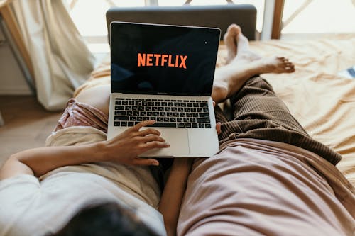 Free A Couple Lying on Bed Watching Netflix on a Laptop Stock Photo