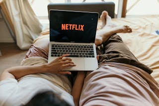 A Couple Lying on Bed Watching Netflix on a Laptop