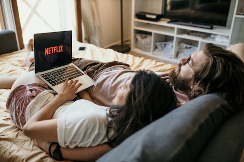 Man and Woman Lying on Bed Using Laptop Computer