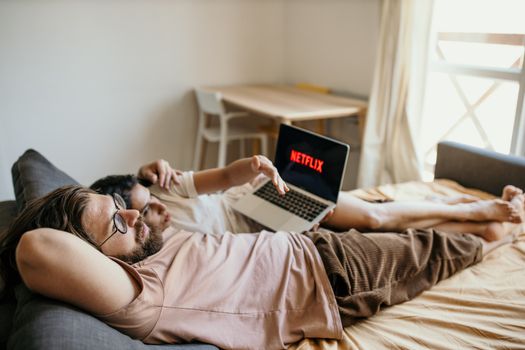A couple lounging on bed watching Netflix, creating a cozy indoor atmosphere.