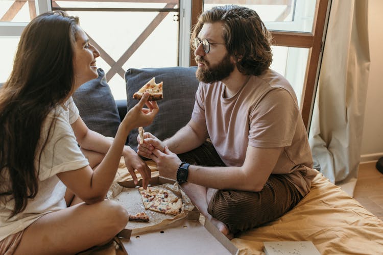 A Couple Having Pizza On The Bed 