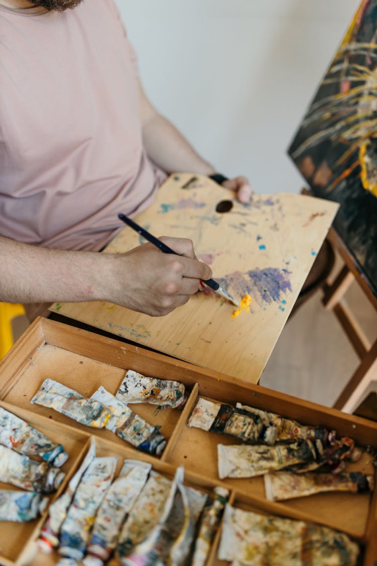 A Person Mixing Colors On A Wooden Board  With A Paint Brush