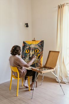 一位艺术家在光线充足的房间里，用画架和颜料在画布上绘制了一幅色彩缤纷的猫肖像