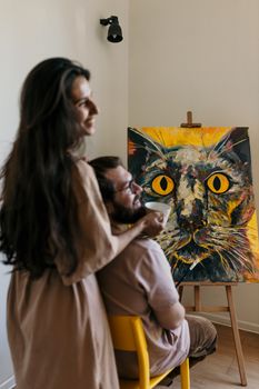 一对夫妇在他们舒适的家中欣赏着一幅充满活力的猫画，画作散发着温暖和创造力