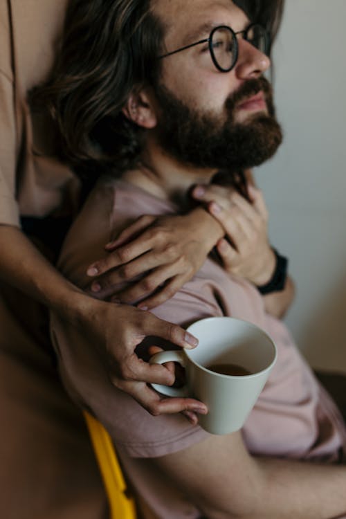 Man in Brown Shirt Holding White Ceramic Mug