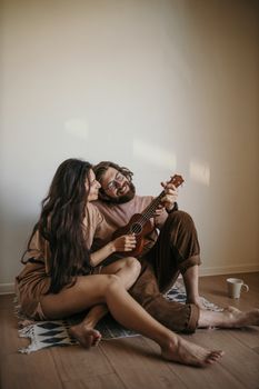 一对夫妇在室内弹奏尤克里里琴，放松身心，营造出舒适迷人的氛围