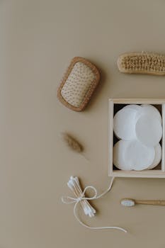 Minimalist flat lay of eco-friendly bath essentials including brushes, toothbrush, and cotton pads.