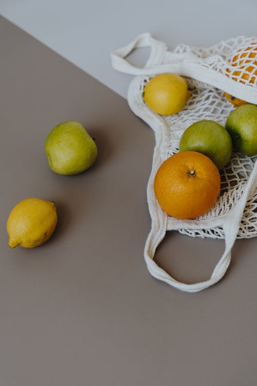 Citrus Fruits and Green Apple on White Mesh Bag