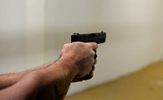 Crop man firing pistol in shooting range
