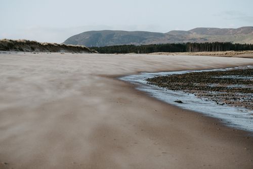 Free Peaceful beach in Scotland with distant mountains, capturing serene natural beauty. Stock Photo