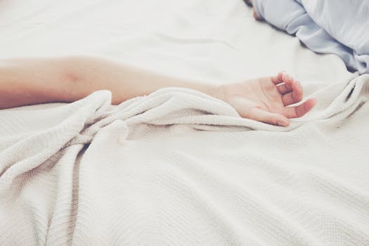 A peaceful morning scene showing a relaxed arm resting on soft linen bedding.