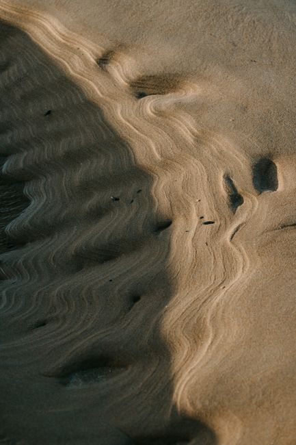 Close-up of intricate sand patterns on a Scottish beach, captured in natural evening light.
