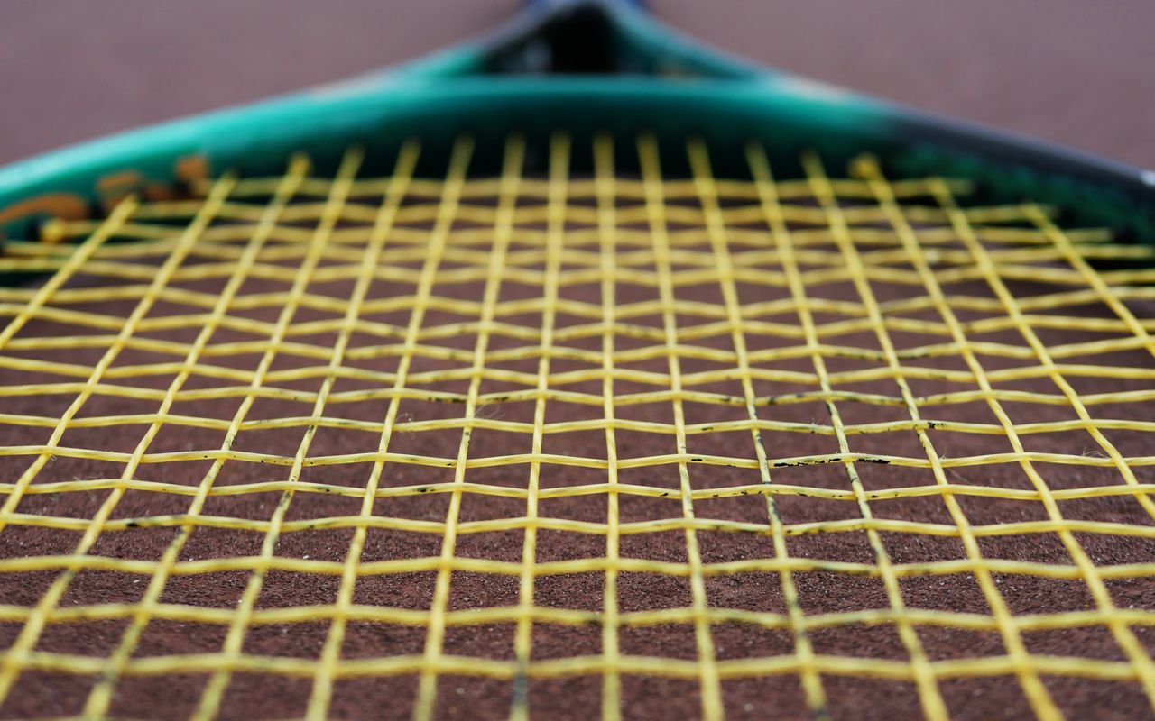 Macro detail of racquet strings crossing at the stringbed