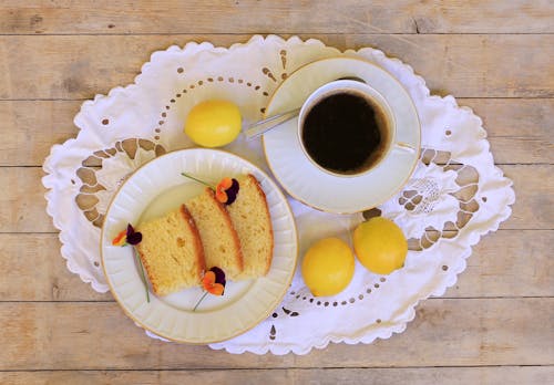 Free Slices of Bread Beside a Cup of Black Coffee with Citrus Fruits on a Wooden Table Stock Photo