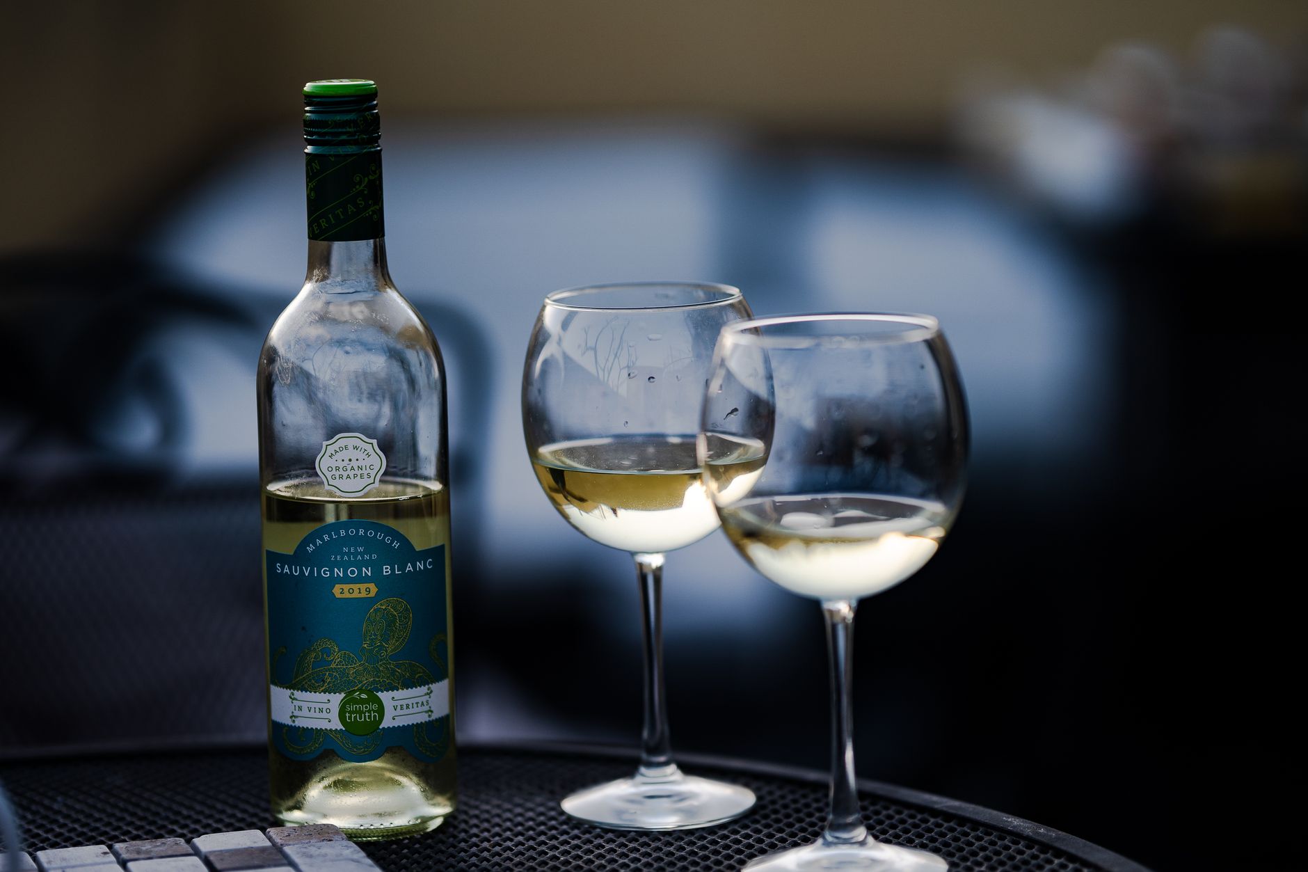 A crisp glass of pale Sauvignon Blanc positioned against a sunlit French vineyard landscape.