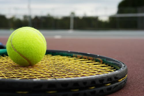 A Green Tennis Ball and Racket on the Floor