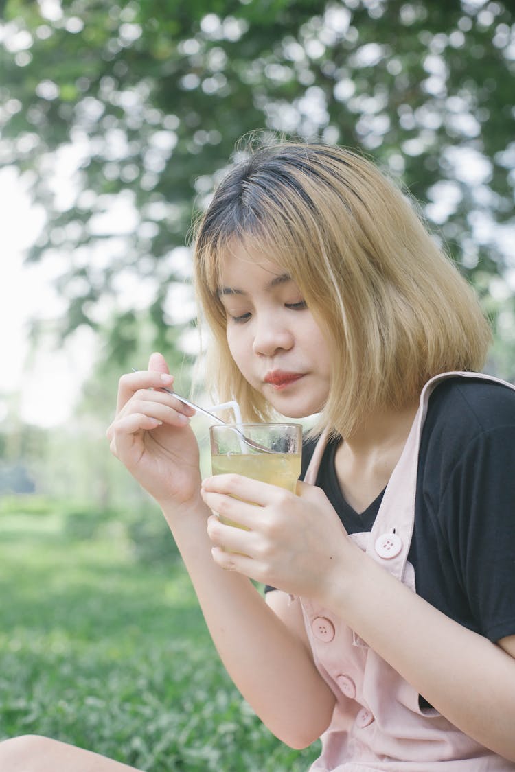 A Young Woman Holding A Glass Of Drink And Spoon