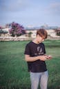 A Man Standing on Green Grass Using Cellphone