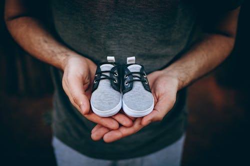 Free Man Holding Baby Shoes Stock Photo