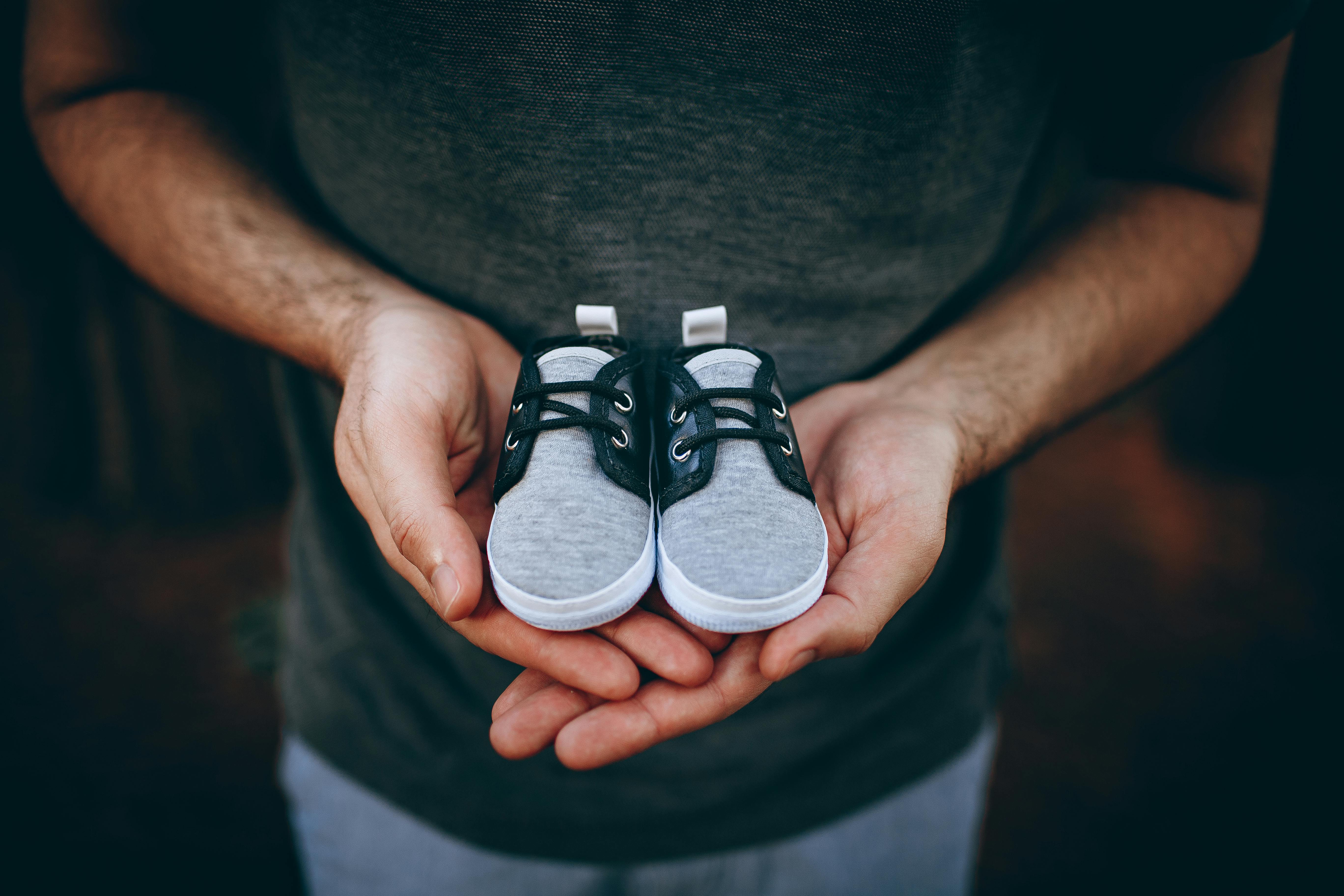 Man Holding Baby Shoes · Free Stock Photo