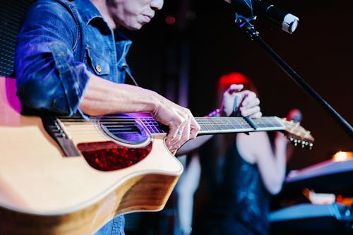 Free A Person in Blue Denim Jacket Holding a Brown Acoustic Guitar Stock Photo