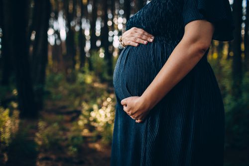 Free Crop unrecognizable pregnant woman holding tummy with both hands while waiting for childbirth Stock Photo