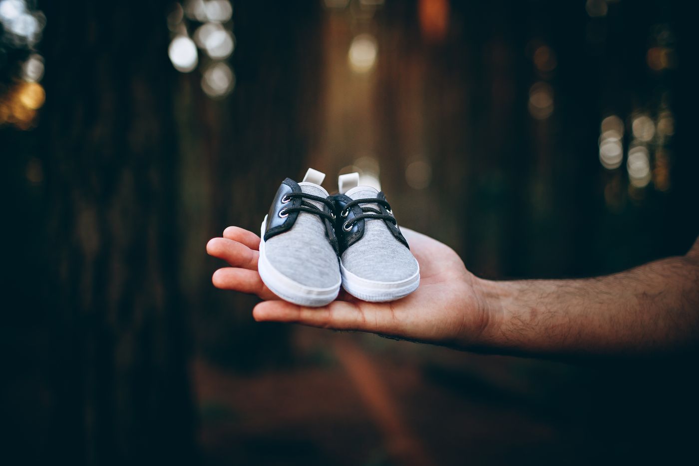 Small gray baby shoes held gently in a parent hand outdoors