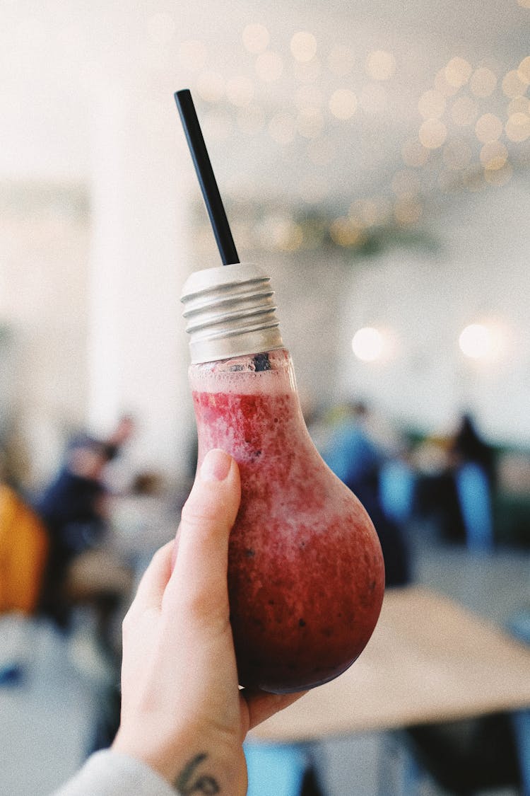 Crop Woman Showing Unusual Smoothie Bottle In Hand