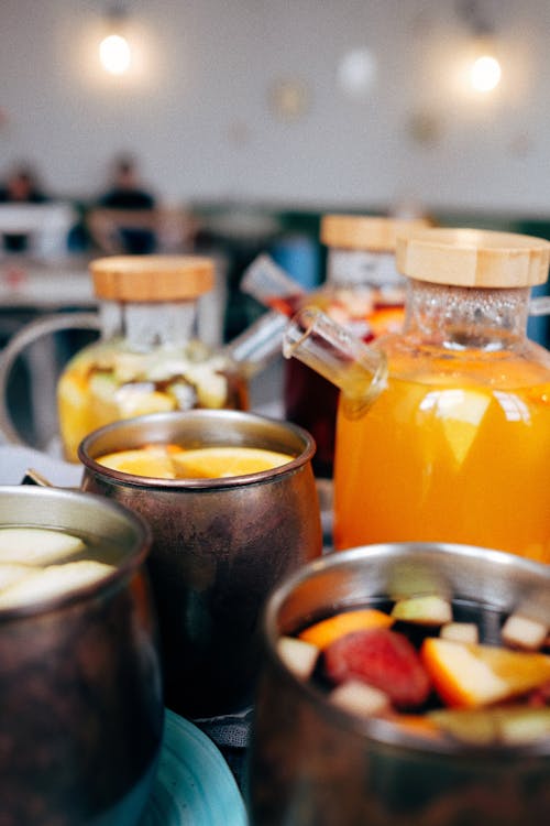 Assorted fresh ice drinks in different kettles on counter in modern restaurant