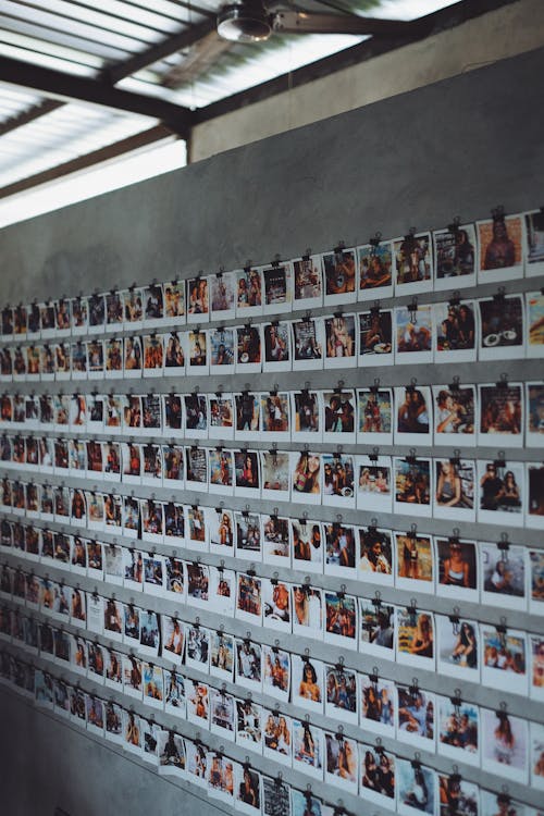 Exhibition of instant photos collection on gray concrete wall inside of modern loft studio