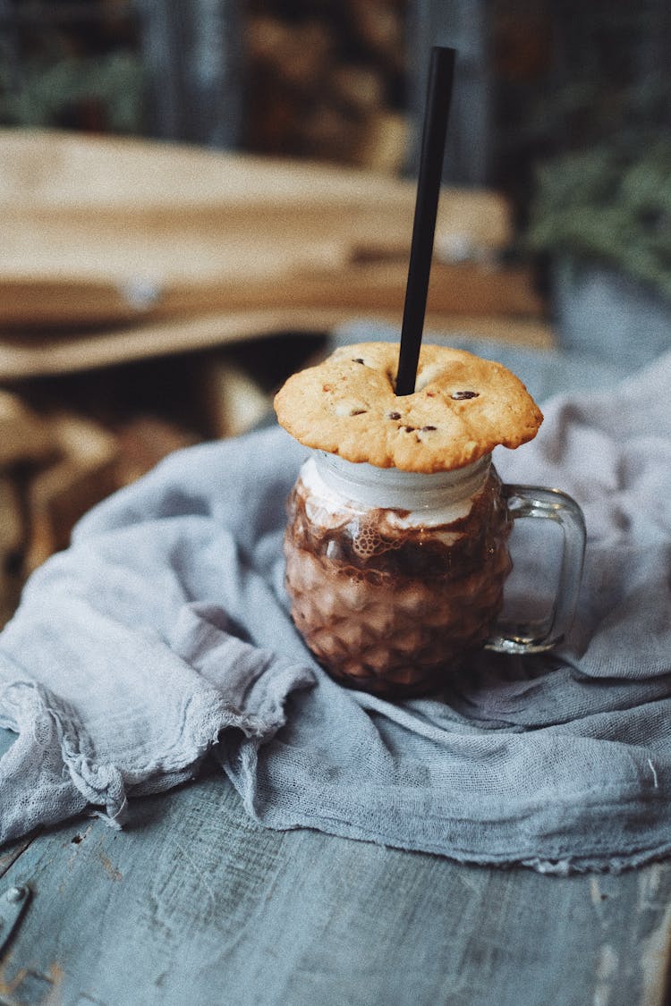 Crispy Cookie On Glass Jar With Cold Coffee Placed On Wooden Table