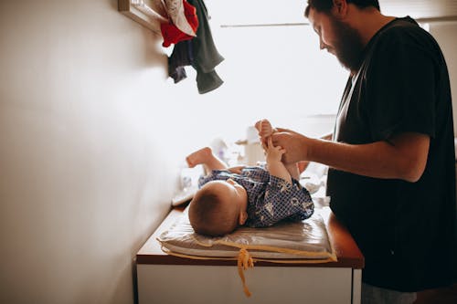 Young father changing diaper of newborn baby