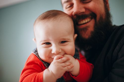 Free A heartwarming close-up of a smiling father holding his joyful baby. Stock Photo