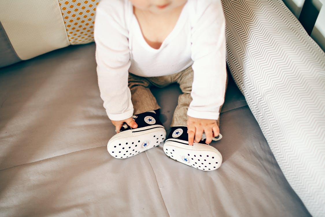 Free Little baby in cool shoes on bed Stock Photo