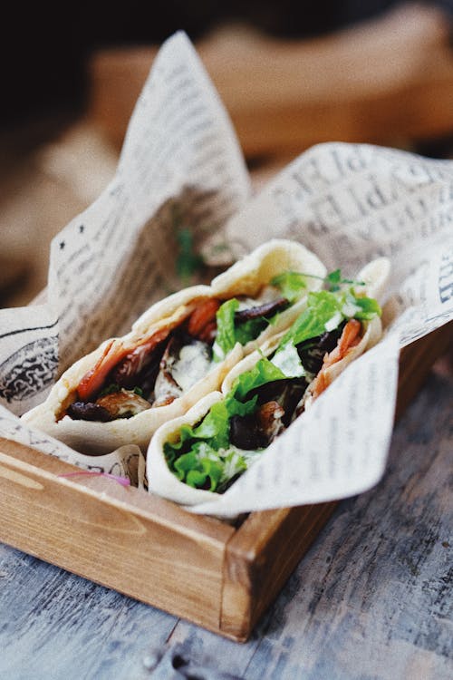 Pita pocket with grilled vegetables and feta cheese on wooden tray