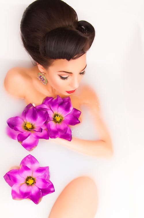 Sensual woman relaxing in foamy bath with delicate flowers