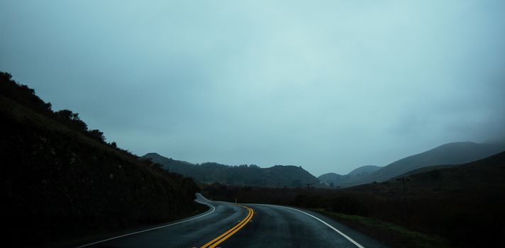 雾霾天，弯曲的柏油路穿行于碧绿葱郁的高地山丘之间